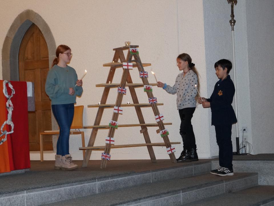 Kerzen werden entzündet und auf eine Lichtpyramide gestellt.