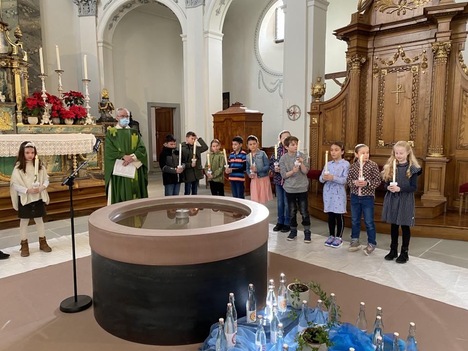 Kinder versammeln sich um den Taufbrunnen